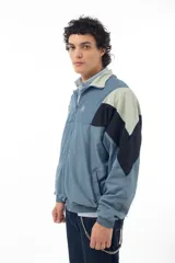 Campera deportiva azul con recortes en negro y verde agua, cierre frontal con cremallera y cuello tipo mao.