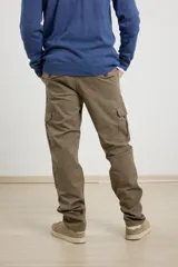 Pantalon cargo de corte recto en color verde militar, confeccionado en sarga de algodón con elastano. Presenta bolsillos laterales con fuelle y tapa, además de bolsillos traseros con cierre de botón.