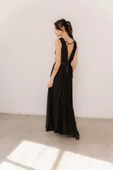 Vestido largo negro, con escote en V profundo ribeteado en ecuero y doble cinto del mismo material que marca la cintura. Cuenta con falda amplia con gran caída y aberturas laterales.