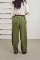 Pantalon de corte amplio y relajado en color verde, con pinzas delanteras, botones decorativos y cinturón de lona incluido.