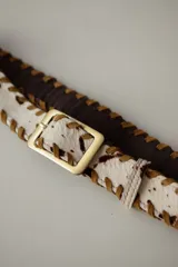 Cinturón de cuero color bordó con costuras de tientos en color azul oscuro a lo largo de los bordes. Posee una hebilla rectangular metálica plateada.