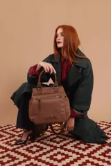 Cartera mochila de diseño versátil, color rosado, confeccionada en material sintético impermeable. Cuenta con doble asa superior, correas ajustables para usar como mochila, compartimento principal con cierre y bolsillo frontal con cierre decorado con tirador largo.