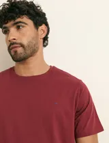 Remera básica de algodón color beige, de manga corta, con cuello redondo y un pequeño detalle bordado en el pecho.