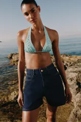 Shorts de denim azul oscuro con tiro alto, calce mom fit y diseño de cinco bolsillos con costuras en contraste.