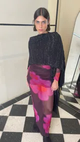 Ruana tejida de color negro con sutiles destellos plateados, diseño de líneas verticales y terminación con flecos largos en los extremos.