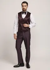 Traje formal de tres piezas en tono tostado brillante, compuesto por saco con solapas en contraste, pantalón de corte recto y chaleco a juego, acompañado de moño.