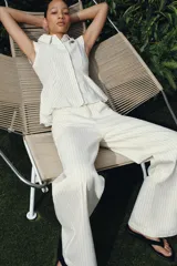 Jeans de tiro alto y corte wide leg, confeccionados en tejido de algodón con diseño de rayas verticales a contraste. Presentan cinco bolsillos, trabillas en la cintura y cierre frontal con cremallera y botón.