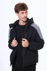 Campera técnica con capucha desmontable, diseño bicolor en negro y gris. Cuenta con cierre frontal termosellado, bolsillos laterales y bolsillo en el pecho con cierre, ideal para protección contra el viento y el frío.