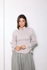 Camisa de tela con estampado de microcuadros, con diseño ajustado mediante frunces en el cuerpo y las mangas, cuello alto con volado y mangas largas con puños acampanados.