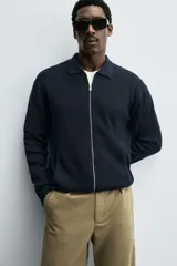 Chaqueta de punto de algodón con textura acanalada, cuello solapa, cierre frontal con cremallera y bolsillos laterales de vivo.