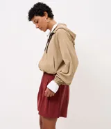 Short femenino Marfinno de modelaje suelto y caída liviana, color verde militar, con cintura con pasadores, pinzas frontales, bolsillos laterales y bajo recto. Incluye un cinturón fino de rafia con hebilla metálica.