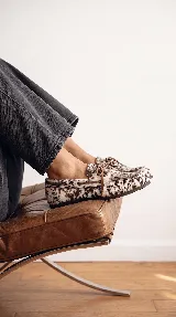 Mocasines náuticos de cuero con pelo natural con estampado animal print tipo vaca, cordones decorativos en el empeine y suela flexible.