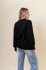 Sweater de tejido fino color beige, con cuello redondo, mangas largas y terminaciones acanaladas. Presenta un diseño con detalles trenzados en diagonal en el frente y corte relajado.