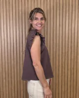 Musculosa a rayas verdes y blancas, con cuello alto fruncido, cierre frontal con botones y volados en los hombros.