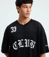 Remera negra de corte boxy y estilo deportivo, confeccionada en tejido de malla de poliéster. Presenta cuello en V, mangas corta, estampado numérico "33" en el pecho derecho y la inscripción "CLUB" en tipografía gótica en el centro.