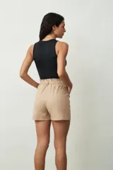 Short de tiro alto con estampado botánico en tonos verdes y crudos. Presenta una cintura elástica con lazo ajustable del mismo tejido, bolsillos laterales y un corte holgado.
