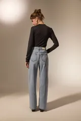 Pantalon de jean de corte recto y tiro medio, con detalle de ojales metálicos a lo largo de la costura lateral externa.