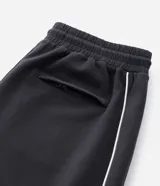 Pantalón deportivo de corte recto y estilo holgado, color negro con una línea vertical blanca en los laterales. Cuenta con cintura elástica con cordón de ajuste y bolsillos laterales.