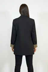 Blazer negro de corte clásico con solapas redondeadas y bolsillos con solapa. Presenta un detalle distintivo de estampado animal print en el interior de los puños, visible al doblar las mangas.