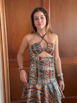 Vestido corto con estampado de rayas horizontales en tonos grises y negros. Diseño con escote halter que se ata al cuello, abertura central en el busto y falda corta con volado.