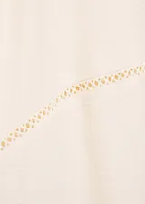Vestido corto de color crudo con cuello en pico, manga corta y detalle de bordado calado en el pecho. Presenta un diseño evasé y cierre de cremallera invisible en la parte posterior.