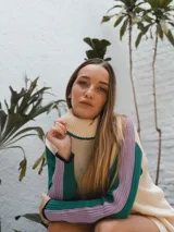 Buzo tejido de punto color crema con cuello alto y mangas largas con rayas horizontales en verde y lila.