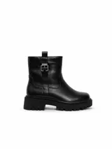 Bota corta de cuero sintético color negro, con suela track dentada y detalle de hebilla metálica en el lateral superior.