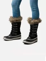 Bota de invierno impermeable Sorel, modelo Joan of Arctic, con exterior de gamuza negra, ribete de piel sintética en la parte superior y base de caucho vulcanizado con suela antideslizante.