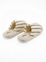 Pantuflas de estar por casa, con diseño de rayas horizontales marrones sobre fondo blanco. Presentan una textura suave y afelpada, con una base acanalada y borde trenzado decorativo.