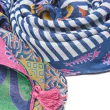 Bufanda larga rectangular de gasa sintética liviana, con estampado multicolor de motivos geométricos y borlas decorativas en los extremos.