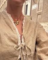 Collar tipo gargantilla con dije de flor metálica de acabado brillante, suspendido de un cordón doble de seda natural teñido a mano en color rojo.