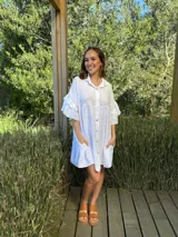 Vestido camisero blanco de lino italiano, con cuello camisero, cierre frontal con botones, mangas cortas con doble volado y bolsillos laterales.