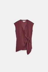 Top fluido sin mangas, de color bordó, con escote en V cruzado y detalle de nudo drapeado en el lateral delantero.