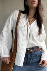 Camisa blanca de manga larga con detalles bordados en las mangas y encaje en el frente y hombros, escote en V con botones frontales.
