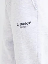 Pantalón de jogging color gris melange, con corte regular y cintura elástica con cordón ajustable. Presenta puños acanalados en los tobillos y un pequeño logo bordado en la parte superior de la pierna izquierda.
