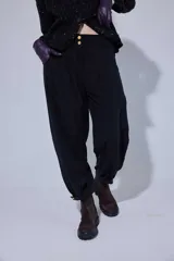 Pantalón tipo bombachita con pinzas que aportan volumen, confeccionado en Tencel. Presenta cierre frontal con botones dorados, bolsillos delanteros y ruedo ajustable mediante botón dorado.