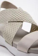 Sandalia negra con tiras cruzadas en el empeine y tira simple. Tira de ajuste en el tobillo. Plataforma de 3 cm de alto.