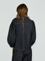 Camisa de denim azul con mangas abullonadas y cuello clásico.