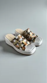 Sandalias de plataforma con capellada de cuero natural pintada a mano con un diseño abstracto en tonos neutros, dorados y terracota, con base y plantilla acolchonada de color blanco.