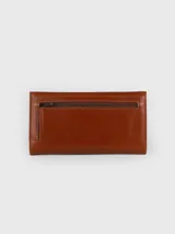 Billetera combinada de cuero en tonos marrón y camel, con solapa frontal de pelo vacuno estampado y detalle de placa con el logo de la marca.