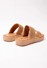 Sandalia con doble tira en el empeine, una de cuero color tostado y otra tejida en rafia. Plataforma de yute de 3.5 cm de alto.
