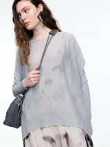 Sweater de manga larga en tejido de punto liviano con lurex, color gris. Su calce relajado y ligeramente oversize le aporta movimiento y transparencia.