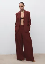 Pantalón de tiro medio color bordó, de diseño wide leg con pinzas delanteras y bolsillos laterales. Cuenta con cierre de cremallera, botón y ganchos ocultos con tapeta, además de forro interior.