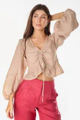 Top de lino italiano color beige, con escote en V, mangas abullonadas y cordón ajustable en el centro del frente.