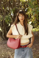 Cartera hobo de cuero color rojo con silueta curva de media luna, cierre superior y correa de hombro ajustable.