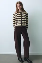 Chaqueta de punto a rayas horizontales en color marrón y beige, con cuello redondo, manga larga y cierre frontal con botones. Incluye una bufanda integrada del mismo tejido y diseño.