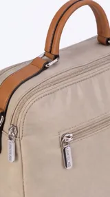 Bandolera de nylon color tostado de formato compacto y estructurado, con asa de mano superior y correa larga desmontable y regulable. Cuenta con cierre principal, bolsillo frontal con cierre bajo solapa y bolsillo trasero con cierre.