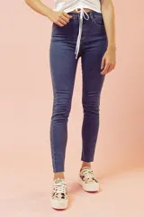 Jeans ajustados de tiro alto en tono azul oscuro, con diseño clásico de cinco bolsillos y terminación desmechada en los tobillos.