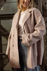 Tapado de paño color rosado, de corte oversized y diseño cruzado. Presenta solapas clásicas, mangas largas con puños vueltos y amplios bolsillos delanteros. Cierre frontal con un botón visible.