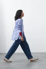 Jean de corte barrel con silueta curva y volumen controlado, de tiro medio y color negro. Presenta un diseño que se ensancha en la pierna y se ajusta levemente en el bajo, con cierre frontal y bolsillos laterales.